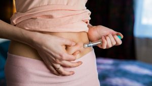 woman giving herself and injection in her abdomen