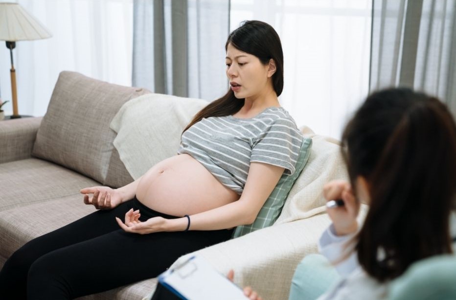 Asian pregnant woman sitting on therapist's couch